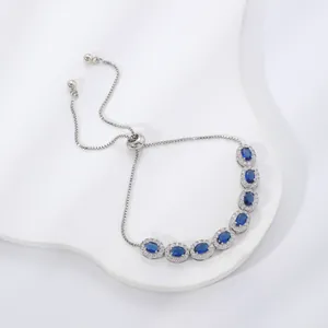 Detail of adjustable silver bracelet with oval blue gemstones and halo zircon accents