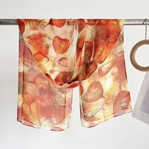 Detailed texture of lightweight leaf pattern scarf in warm orange and yellow tones
