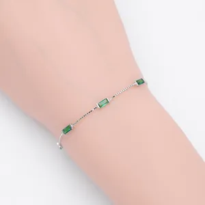 Detail of elegant silver box chain bracelet with three rectangular green gemstones