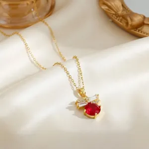 Macro detail of gold necklace featuring red round stone and clear zircon on silk