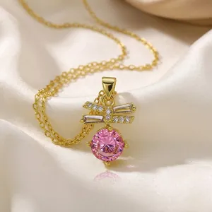 Detail of gold necklace with bowknot zircon design and round pink gemstone on silk