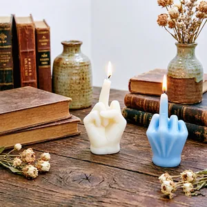 Creative middle finger hand gesture scented candles in cream and blue on a vintage wooden desk