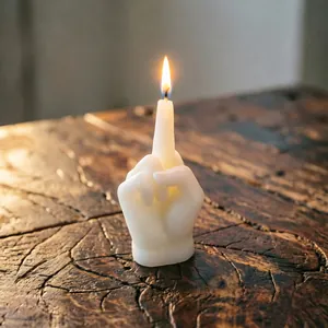 Close-up of a lit middle finger gesture candle on a textured wooden surface