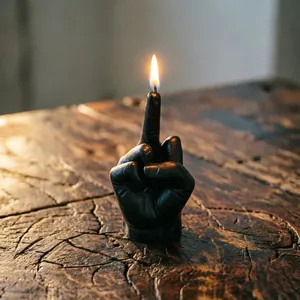 Creative black middle finger gesture scented candle burning on a rustic wood surface