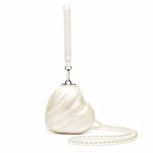 Detail of heart-shaped acrylic clutch with pearlescent finish and pearl chain strap