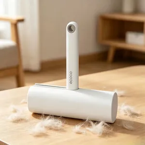 Minimalist lint roller with white handle and sticky paper shown on a wooden surface