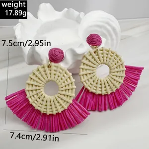 Detail showing fuchsia raffia fan-shaped tassel earrings with bohemian woven texture