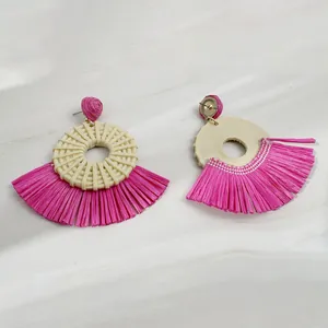 Macro view of Bohemian raffia fan-shaped earrings with vibrant pink woven fringe details