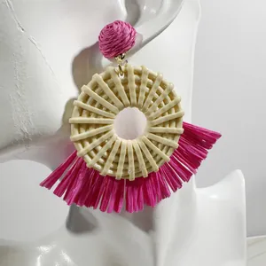 Close-up of pink raffia fan earrings with woven textures on a model mannequin