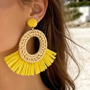 Close-up of bohemian fan-shaped raffia flower earrings with yellow fringe details