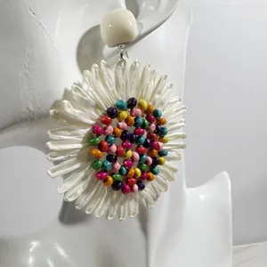 Detail of fan-shaped raffia flower earrings with colorful beads on a white mannequin