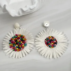 Close-up of fan-shaped sunflower earrings with colorful beads and white textured petals