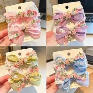 Detail of handmade lace bow hair clips with pearls and floral embroidery in four colors
