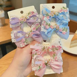 Detail of lace hair clips with embroidery and faux pearls in purple blue and pink colors