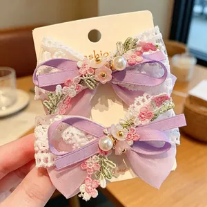 Detail of lavender chiffon and white lace bow hair clips with pearls and pink embroidery