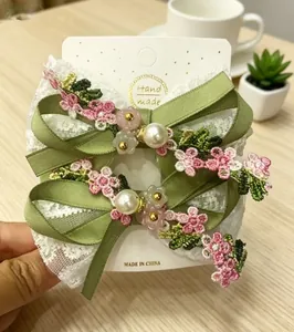 Detail of handmade lace and satin hair clips with cherry blossom embroidery and pearls