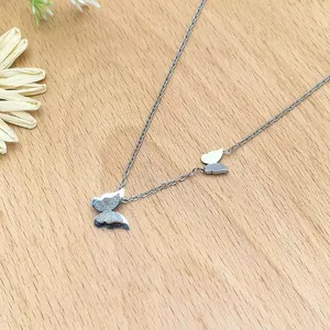Silver double butterfly pendant necklace in polished steel on a rustic wood background