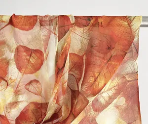 Detail of leaf pattern chiffon scarf with golden edge stitching and sheer texture