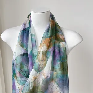 Detail shot of lightweight chiffon scarf featuring vibrant colorful leaf patterns on mannequin
