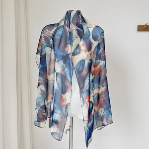 Detailed close-up of translucent thin silk scarf featuring elegant leaf print patterns