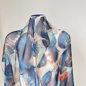 Detail of thin chiffon scarf showing elegant blue and orange leaf patterns on cream fabric