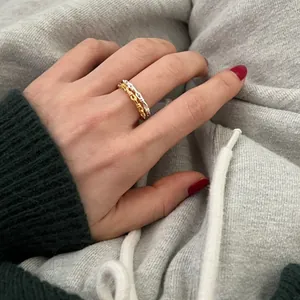 Close-up of gold and silver chain rings worn together with red nail polish