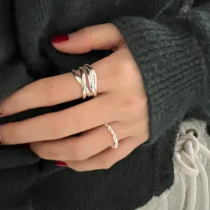 Detail of 925 sterling silver knotted braid ring and fine chain band on model hand