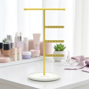 Gold metal jewelry stand with T-bar and earring holes on white marble base tray