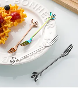 Detailed close-up of leaf-shaped stainless steel dessert forks in four metallic finishes