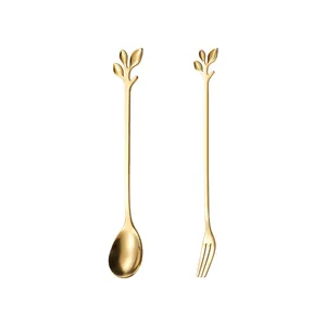 Golden stainless steel spoon and fork set with elegant leaf design on white background