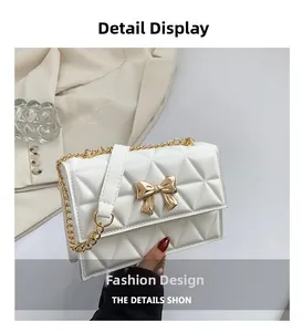 Close-up of white quilted handbag featuring a golden bow-shaped metal lock and chain