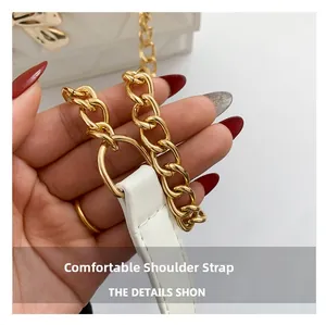 Close-up of white leather shoulder strap and thick gold metal chain on small square bag