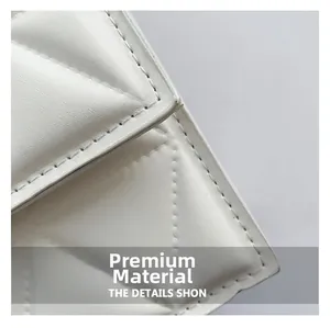 Close-up of white quilted rhombus pattern and fine stitching on faux leather shoulder bag