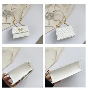 Detail view of white quilted shoulder bag showing gold bow buckle and interior compartments