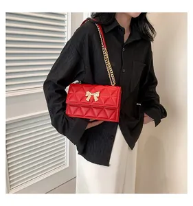 Red quilted leather shoulder bag with golden bow clasp on elegant model outfit
