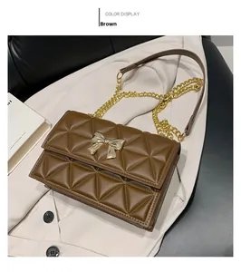 Close-up of brown quilted PU leather shoulder bag with golden butterfly bow buckle