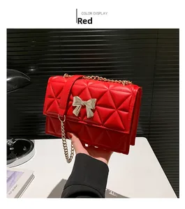 Detail of red quilted PU leather shoulder bag with golden bow clasp and chain strap