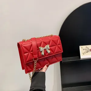 Red quilted faux leather shoulder bag with gold bow clasp and metal chain strap