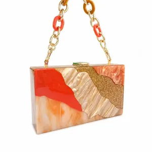Detail of acrylic evening clutch with marble texture拼接 and gold resin chain strap