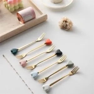 Detailed view of 7-piece stainless steel fruit forks with colorful heart handles and gold finish