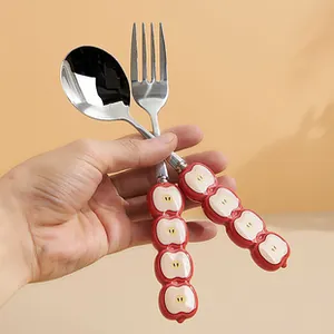 Detail of stainless steel spoon and fork with creative red apple cartoon handles