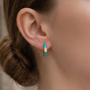 Chic turquoise enamel huggie earrings with gold plating worn by a model in a side view