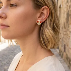 Close-up of 18K gold smile earring with white zircons and red stars on a female model