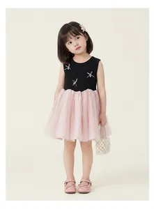 Detail of girls' dress showing pink ribbon bow with pearl accents on black ribbed bodice