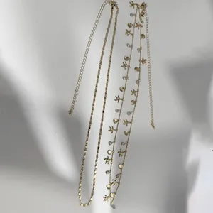 Detail of gold beach necklaces with starfish shell charms and beaded accents on white