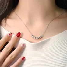 Close-up of a beaded feather pendant necklace worn by a model with a silver finish