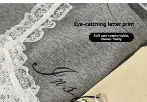 Detail of grey knitted fabric featuring white lace trim and black cursive letter print