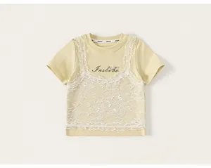 Close-up of girl's yellow T-shirt featuring white lace layers and black cursive print