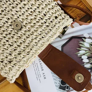 Close-up of handmade woven straw bucket bag with brown leather strap and magnetic closure