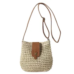 Handwoven straw bucket bag with brown faux leather strap and snap closure for vacation